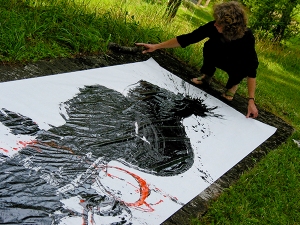 Long Medium shot photograph of black calligraphy stroke with red small stroke painted by Barbara Bash using a big brush on white paper outside on the grass