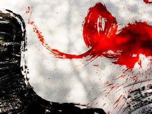 Closeup photograph of red and black calligraphy strokes on white paper using a big brush